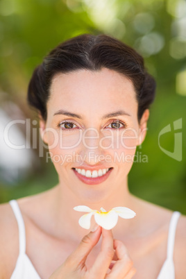 Happy brunette holding a white flower