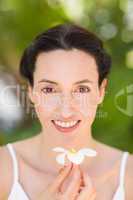 Happy brunette holding a white flower
