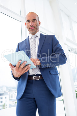 businessman using a tablet and smiling at the camera