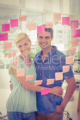 Business partners posing in front of pink heart posts it