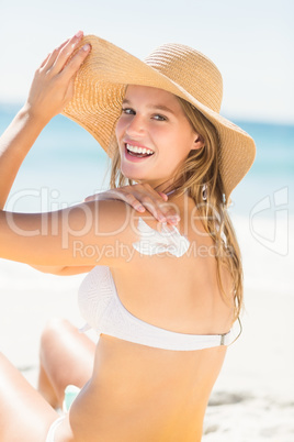 Pretty blonde woman spreading sun tan lotion on her shoulder
