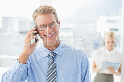 Businessman having a phone call with colleague in background