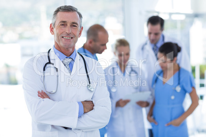 Doctor smiling at camera while his colleague discussing Doctor smiling at camera while his colleague discussing