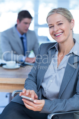 Smilling businesswoman texting on her mobile phone