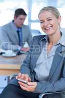 Smilling businesswoman texting on her mobile phone