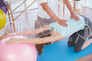 Trainer working with woman on exercise ball