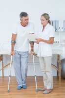 Doctor showing clipboard to her patient with crutch