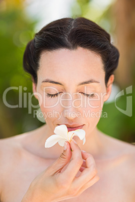 Happy brunette holding a white flower