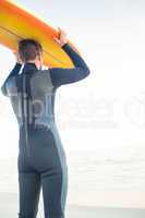 Man in wetsuit with a surfboard on a sunny day