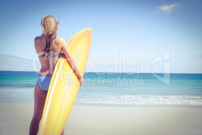 Pretty blonde woman holding surf board