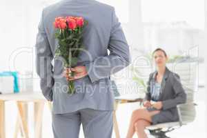 Businessman holding flowers behind his back