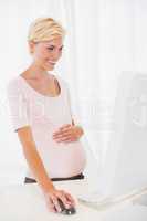 Smiling of a blonde pregnant using computer