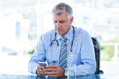 Serious doctor texting with his mobile phone