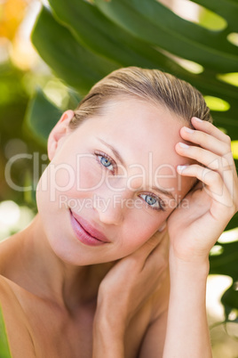 Beautiful blonde smiling at camera behind leaf