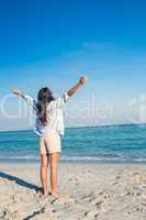 Happy woman with arms outstretched at the beach