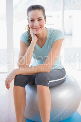 Woman looking at camera and sitting on exercise ball