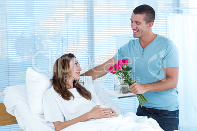 Handsome man offering bouquet of flowers to his pregnant wife