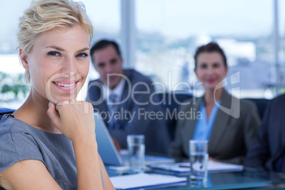 Businesswoman smiling at camera with colleagues behind