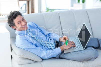 Happy businessman doing online shopping on couch