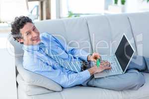 Happy businessman doing online shopping on couch