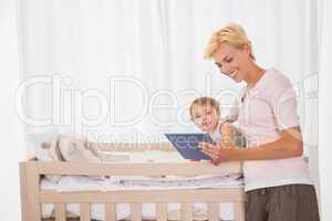 Smiling blonde woman with his son using digital tablet