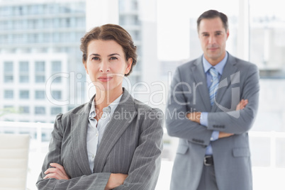 Businesswoman looking at camera with colleague in background