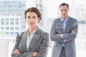 Businesswoman looking at camera with colleague in background
