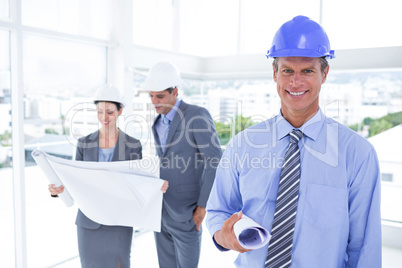 Businessmen and a woman with hard hats and holding blueprint