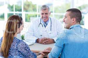 Smiling doctor looking at happy couple