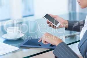 Businesswoman using smartphone and tablet