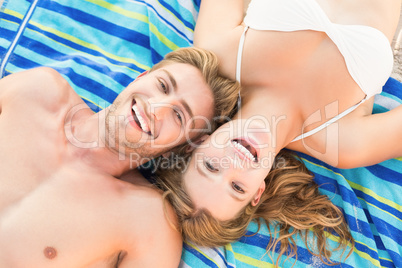 smiling couple lying on a towel looking at camera