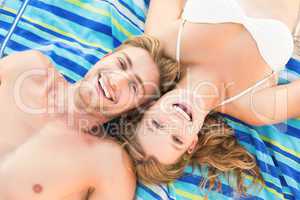 smiling couple lying on a towel looking at camera