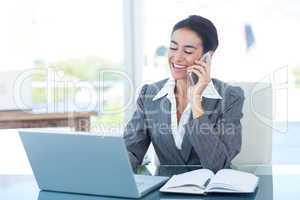 Businesswoman on call and using her laptop