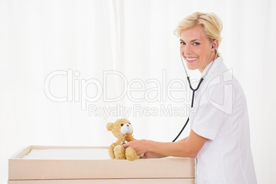 Portrait of a blonde doctor with stethoscope and teddy bear