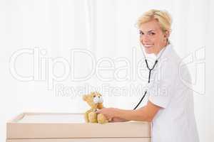 Portrait of a blonde doctor with stethoscope and teddy bear