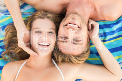 smiling couple lying on a towel looking at camera