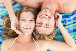 smiling couple lying on a towel looking at camera