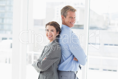 Smiling businesswoman back-to-back with colleague