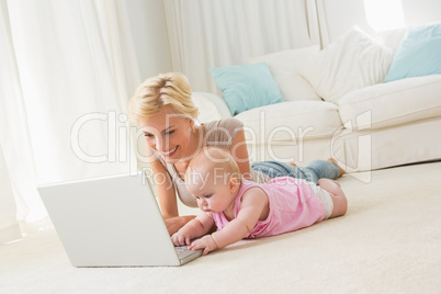 Happy blonde mother with her baby girl using laptop