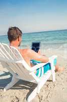 Man using digital tablet on deck chair at the beach