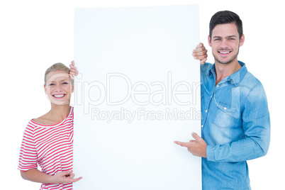 Smiling couple pointing at blank sign in their hands