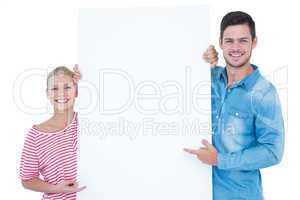 Smiling couple pointing at blank sign in their hands