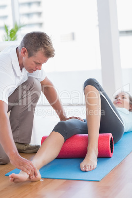 Trainer working with woman on exercise mat