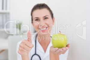 Smiling doctor showing apple with thumbs up