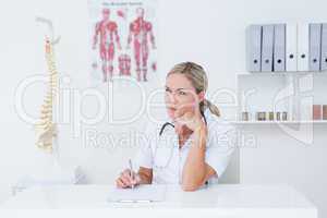 Doctor writing on clipboard at her desk