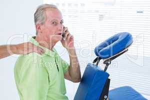 Man having back massage while talking on the phone