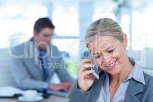 Businesswoman having a phone call with colleague in background