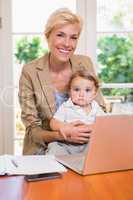 Smiling pretty blonde with his son using laptop