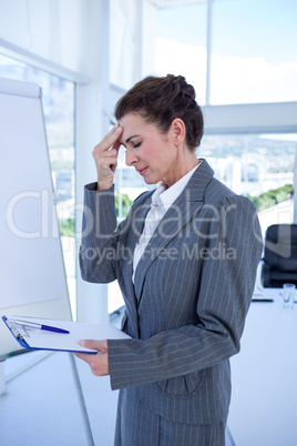 Irritated businesswoman looking at clipboard