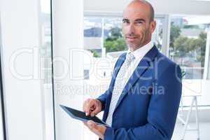 businessman using a tablet and smiling at the camera